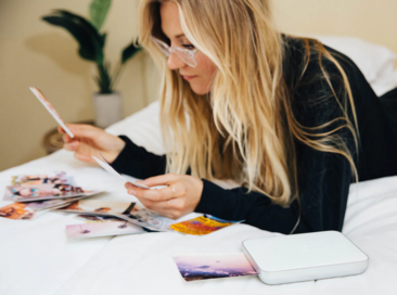 A woman looking at images being printed beside her from a Lifeprint photo printer