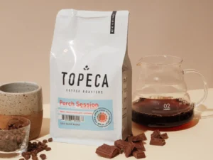 Topeca coffee bag with glass carafe, ceramic mug, and chocolate.